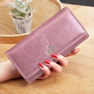 Long leather women's wallet with coin pocket and card slots, featuring a sleek design and branding details.