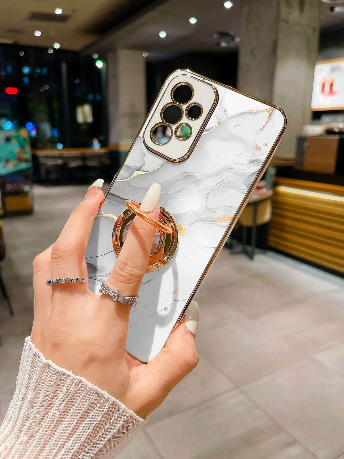 Slim phone case with ring stand featuring a marble pattern, designed by Corporación Turística, shown on a smartphone.