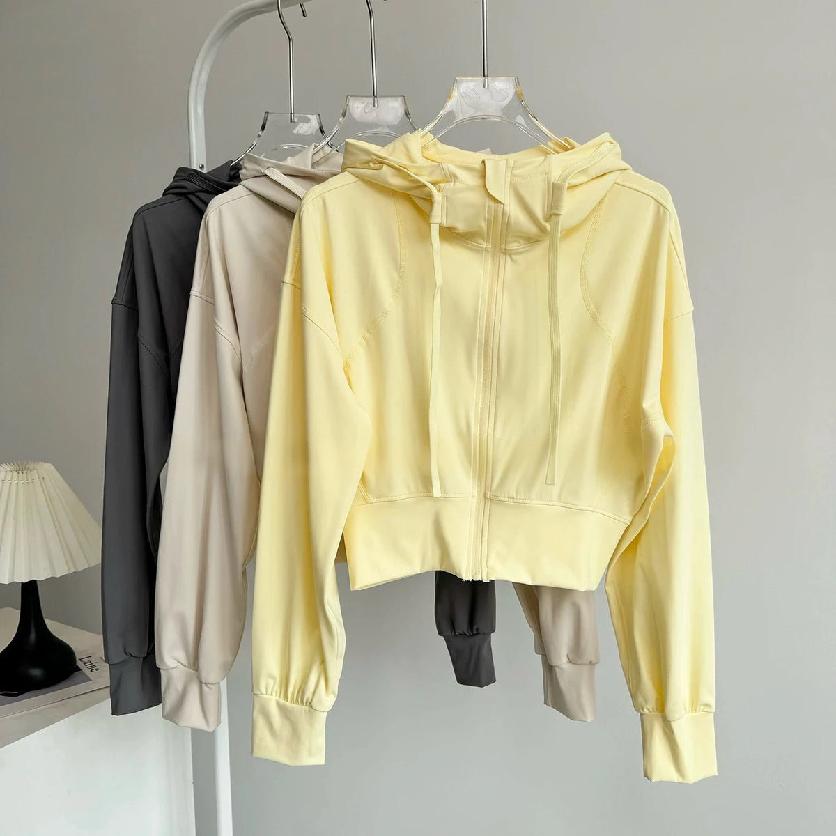 Black breathable women's sports jacket for running and yoga, from Corporación Turística, shown on a hanger with a close-up view.