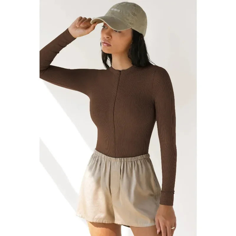 Long-sleeve cream ribbed jumpsuit for women from Corporación Turística, shown on a model, highlighting the fitted style and fabric texture.