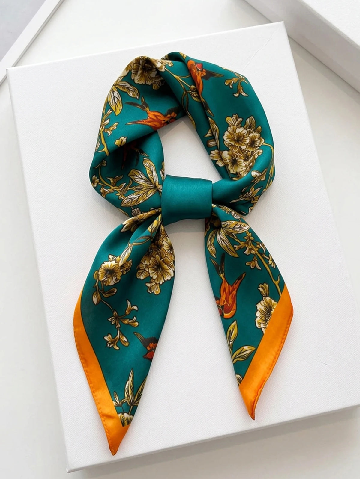 Square silk-like scarf from Corporación Turística featuring a vibrant, detailed pattern in bright colors.
