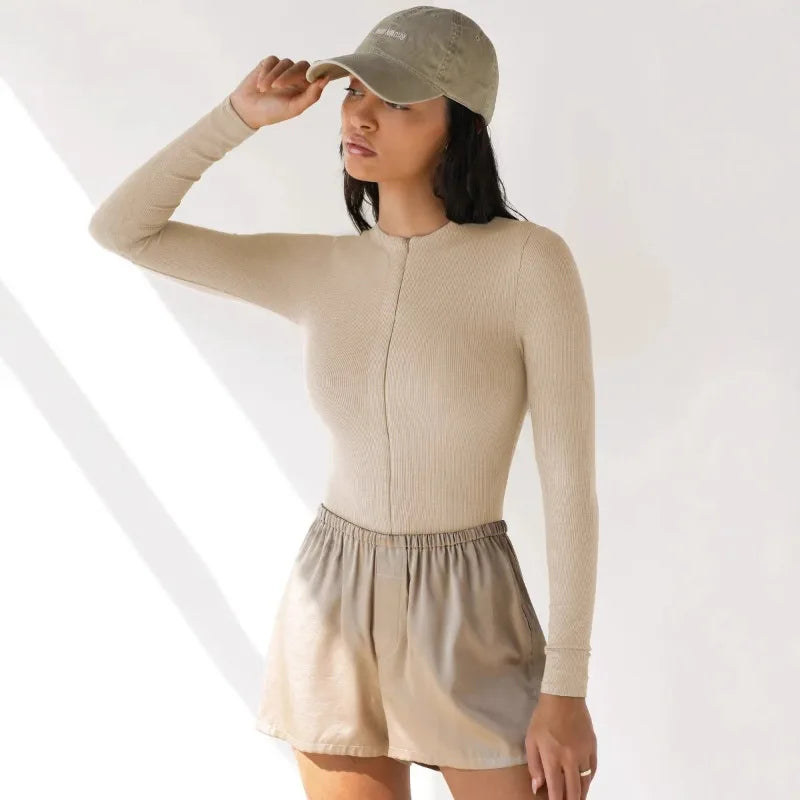 Long-sleeve cream ribbed jumpsuit for women from Corporación Turística, shown on a model in a fashion photoshoot.