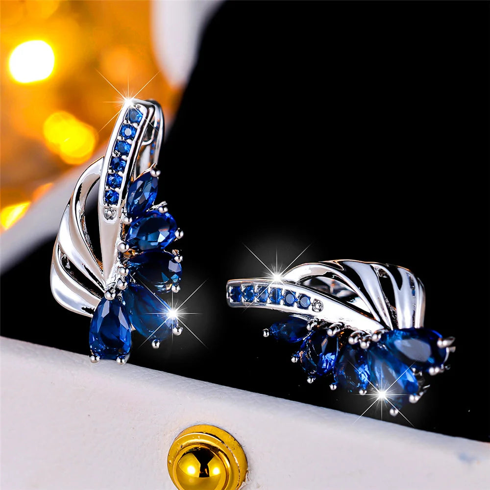 Luxurious clip-on earrings with green and blue gemstones for women, featuring elegant design by Corporación Turística.