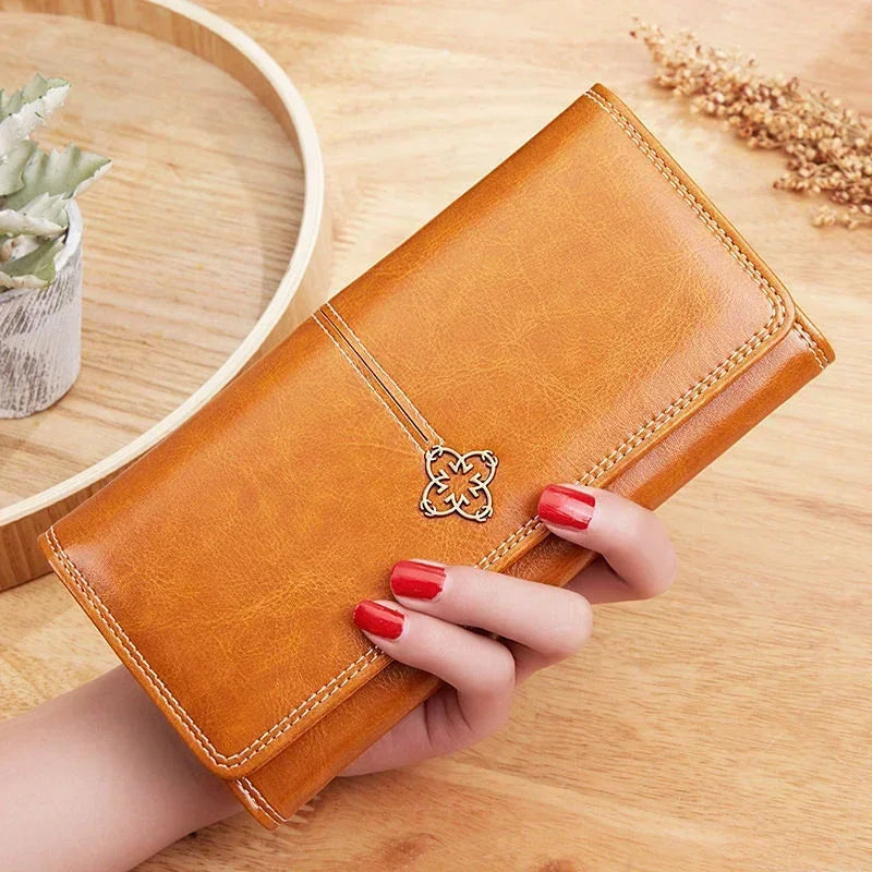 Long women's leather wallet with coin pocket and card slots, crafted by Corporación Turística, shown in black with multiple compartments.
